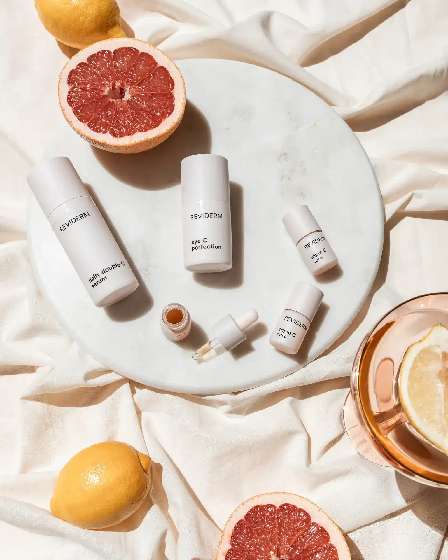 REVIDERM-Flaschen auf einer Marmorplatte, daneben aufgeschnittene Grapefruit und Zitronen