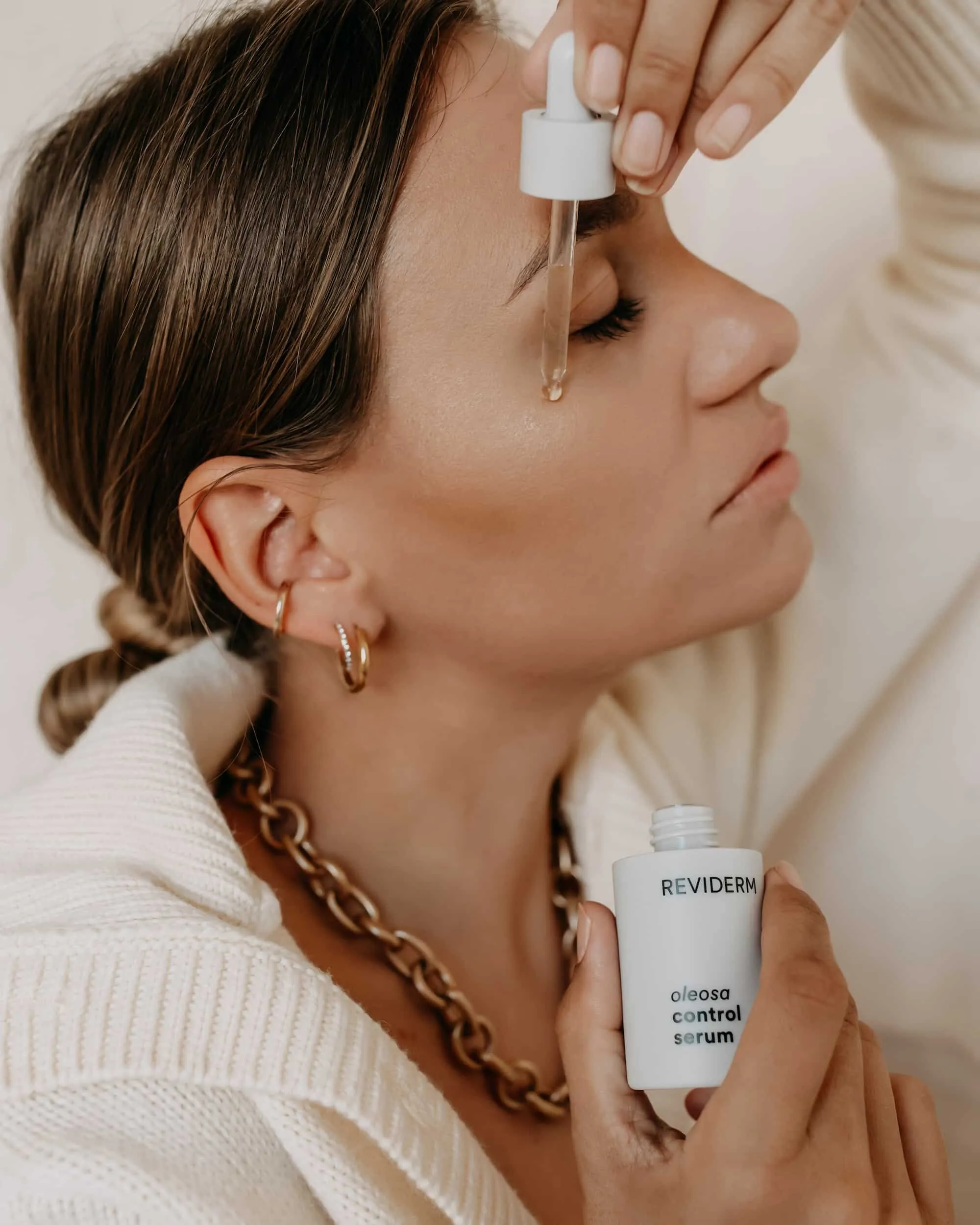 Serum wird mit einer Pipette im Gesicht aufgetragen, die Flasche in der anderen Hand